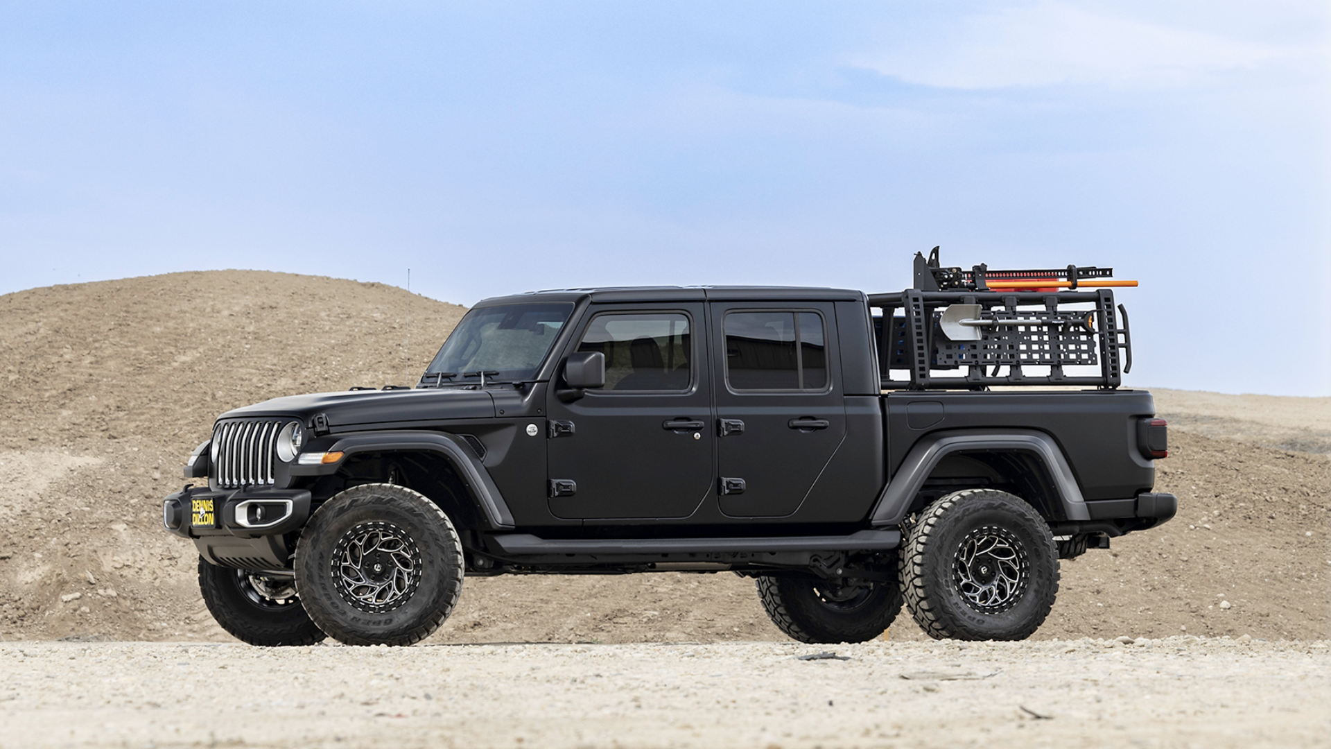 Black Jeep Gladiator outfitted with overlanding gear parked on a rocky desert road