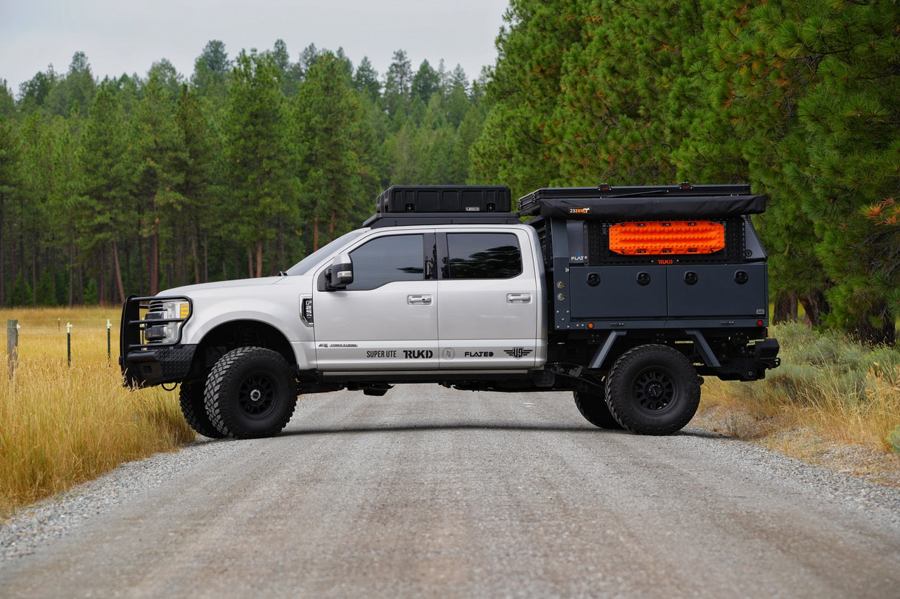 Grey F250 mid size truck with Next Jump Flatbed on dirt road